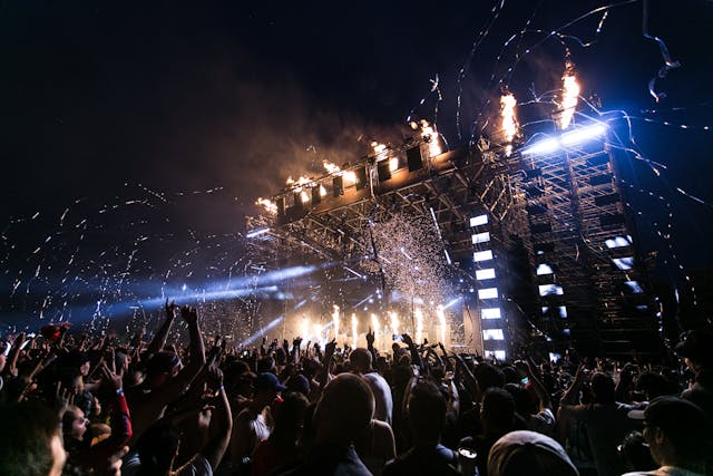 A huge audience flocks toward an outdoor concert. 