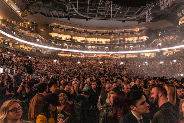 Decine di migliaia di persone si riuniscono in uno stadio gigante per un evento dal vivo. 