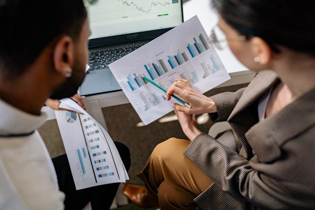 Two professionals discuss TikTok audience graph data on printouts.
