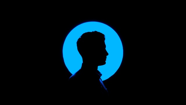 The silhouette of a man in front of a blue circle and a larger black background.