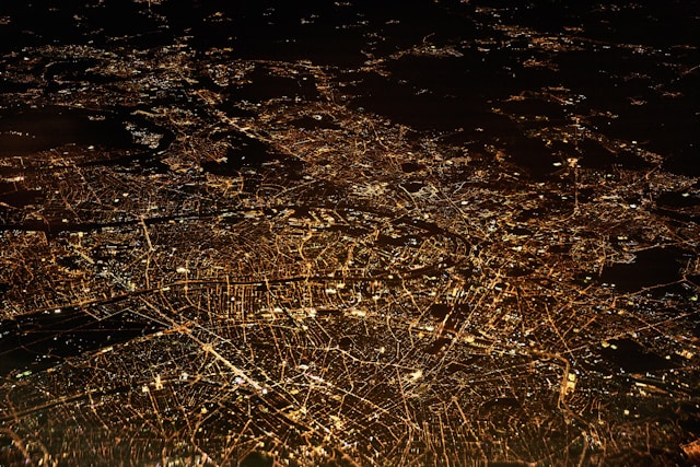 An aerial view of a city shows places lighted up at night. 
