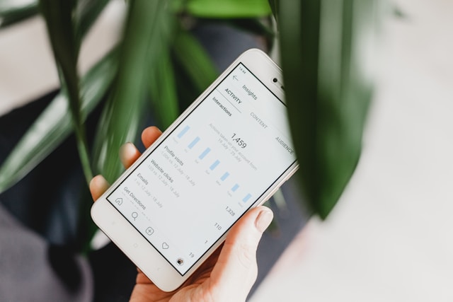 A person holds a smartphone that displays the Instagram Insights page.
