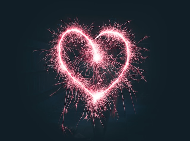 Red sparklers form the shape of a heart. 
