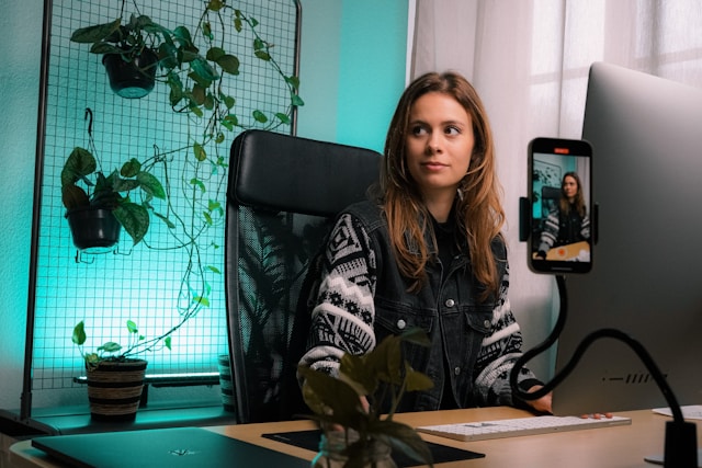 Una creadora se sienta frente a su mesa y su smartphone mientras graba un vídeo para su público de TikTok. 