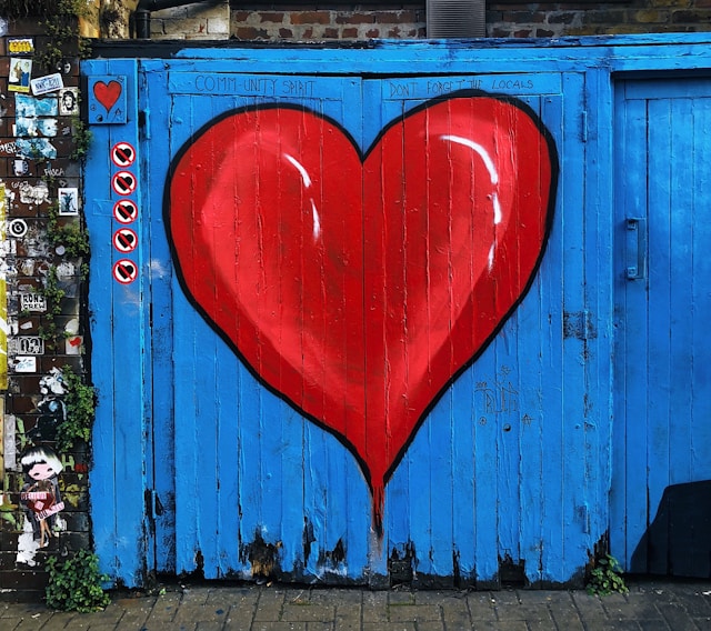 Ein blaues Scheunentor aus Holz mit einem großen roten Herz darauf.
