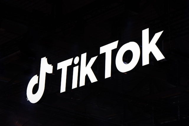 Het TikTok-logo en de naam tegen een zwarte achtergrond. 