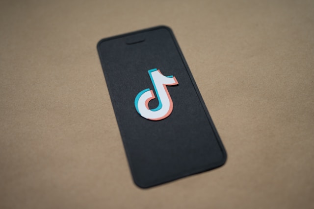 Uma tela de telefone borrada em um fundo marrom exibe o logotipo do TikTok.