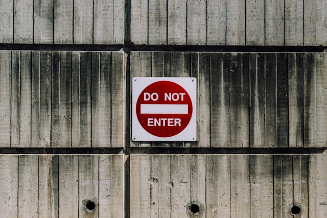 Un cartel rojo y blanco en una pared dice: "No entrar".
