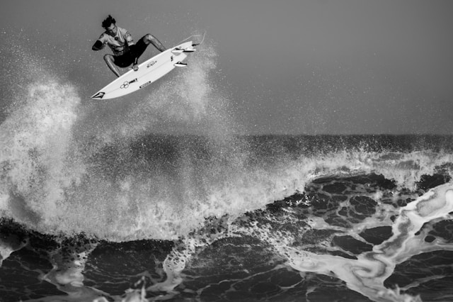 Ein Surfer befindet sich mitten im Sprung auf einer großen Welle.