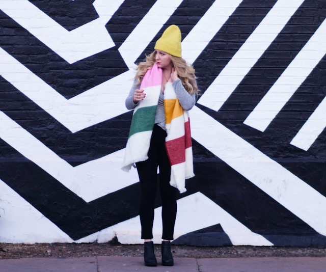 Een influencer staat voor een zwart-witte muur en modelleert kleding voor een gesponsorde post.