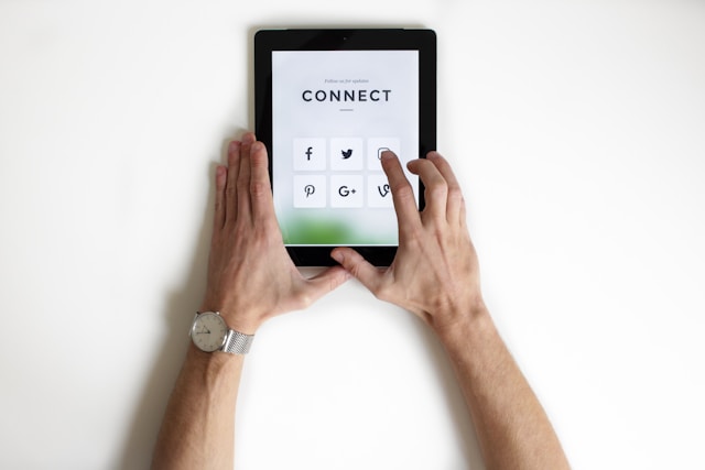 A person taps an app icon on their tablet, which displays various social media apps. 
