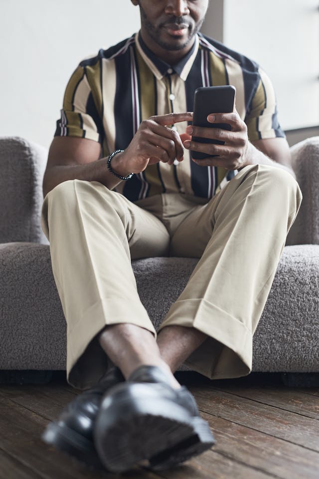 Un homme en chemise rayée tapote sur l'écran de son téléphone.