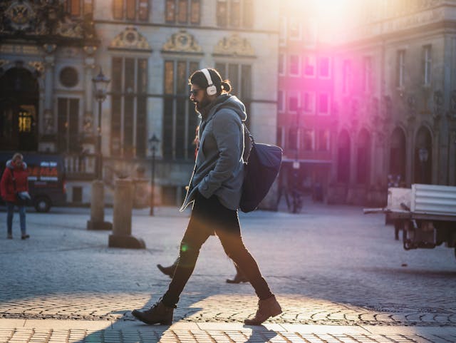 Um homem com fones de ouvido atravessa a rua.