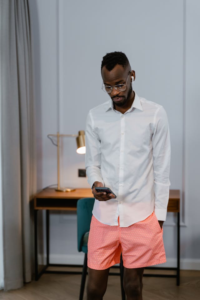 A man looks down while he scrolls his phone.
