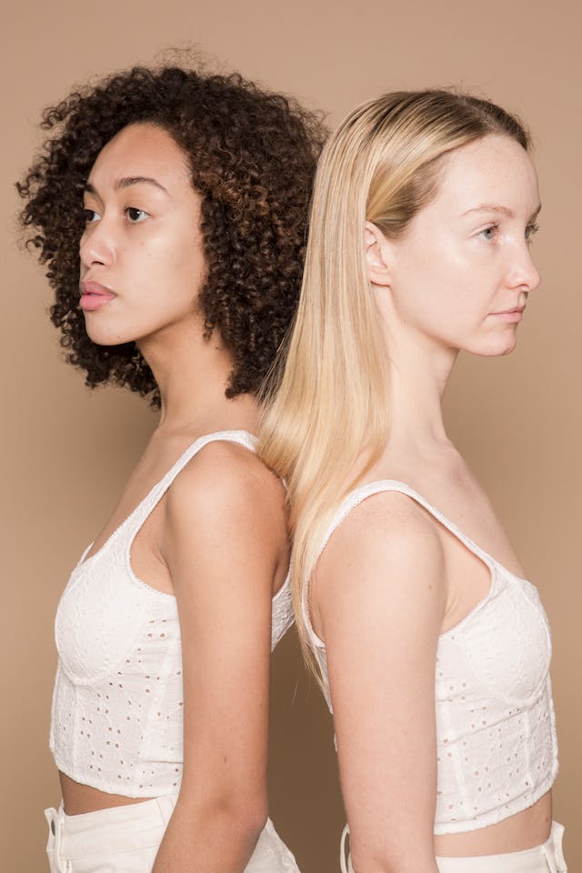 Two women stand with their backs against each other.