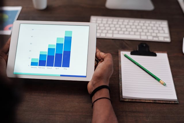 A person holds a tablet displaying a bar chart.