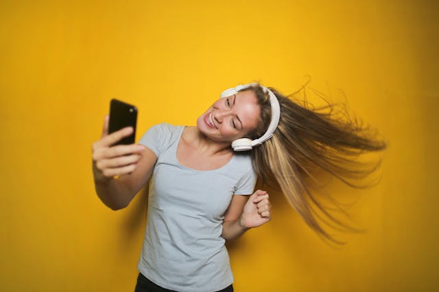 A woman dances while watching a TikTok video.
