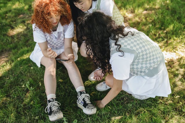 A group of girls gather around a cell phone.
