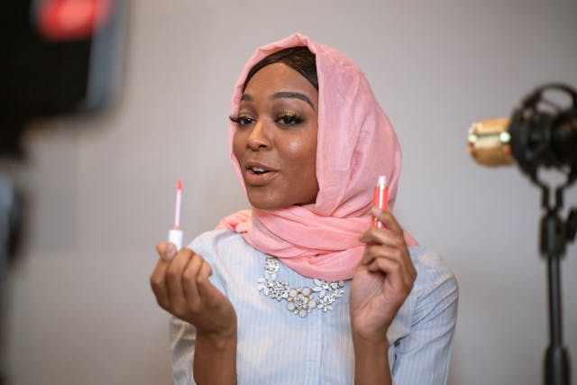 O femeie în hijab înregistrează un videoclip de machiaj.
