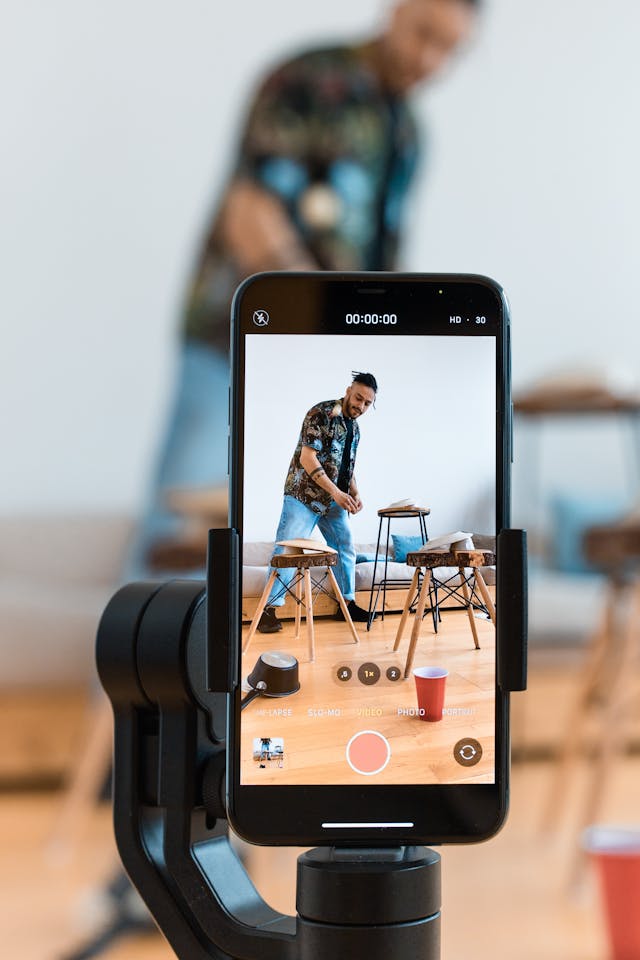 A cell phone on a tripod records a man creating content.