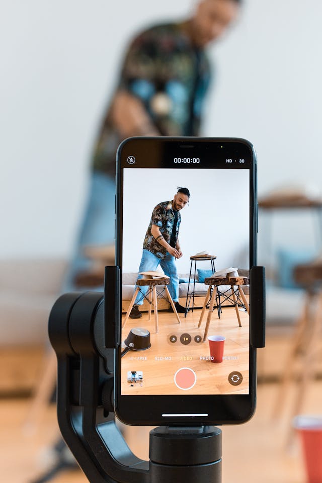 Een mobiele telefoon op een statief registreert een man die content creëert.