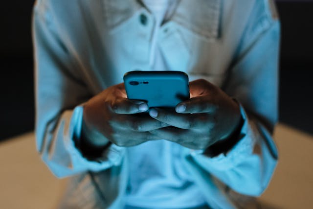 Une personne tient son téléphone à deux mains.