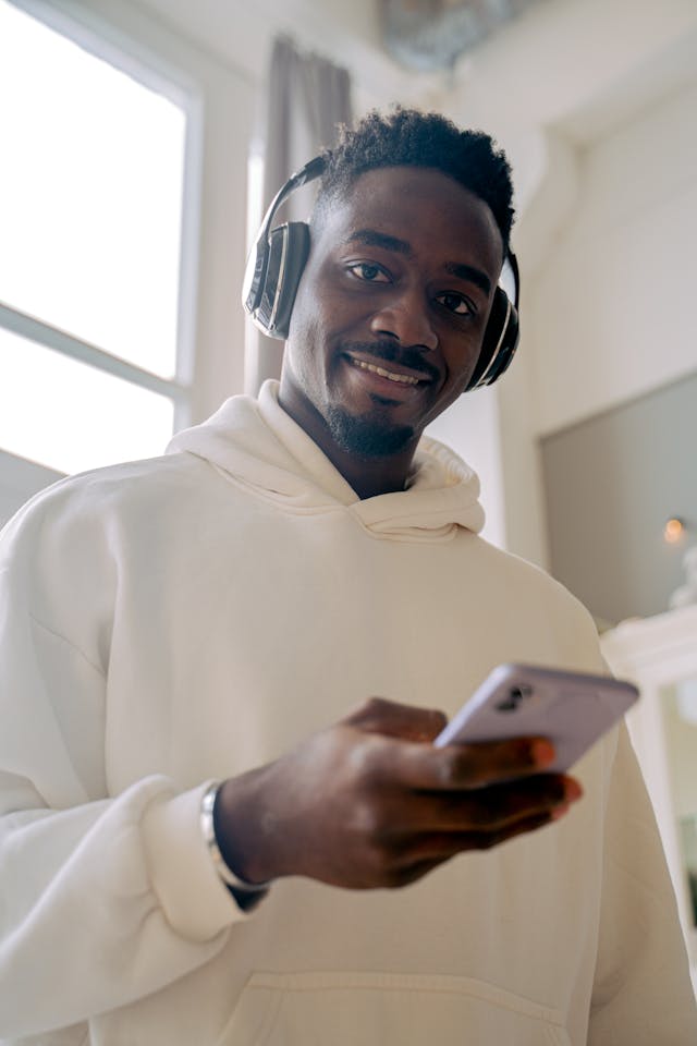 A man smiles while scrolling on his phone.
