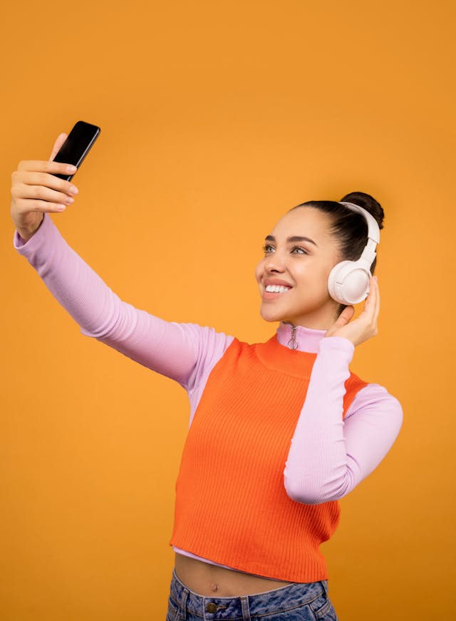 Een vrouw neemt een selfie terwijl ze een koptelefoon draagt.