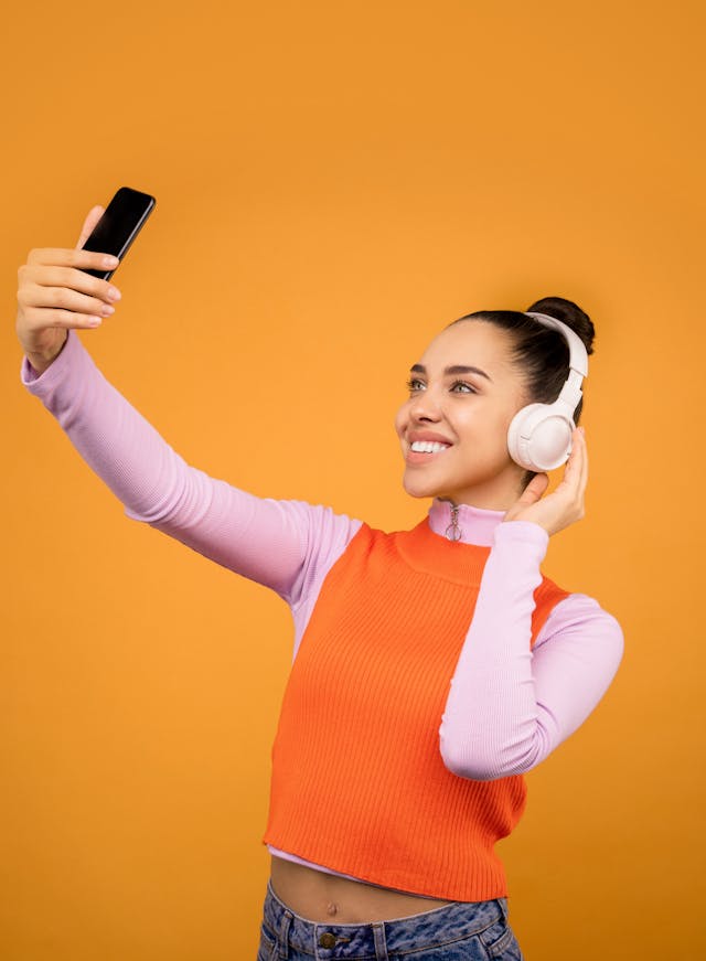 Une femme prend un selfie en portant des écouteurs.