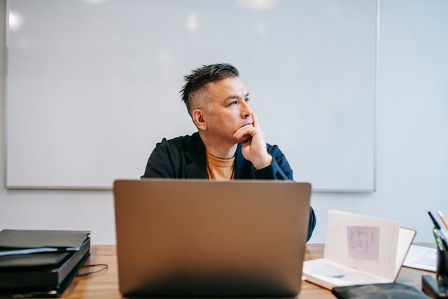 Um homem em profundo pensamento senta-se em frente ao seu laptop. 