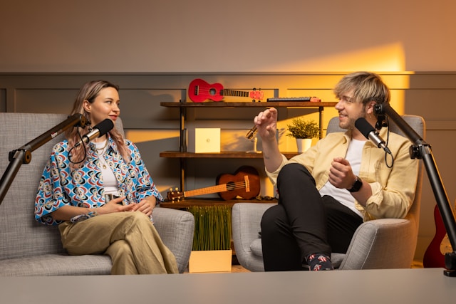 Dois criadores de conteúdo sentam-se em sofás em frente a microfones para um vídeo do TikTok.