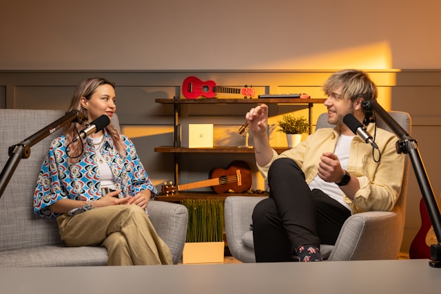 Two creators sit on couches in front of microphones for a TikTok video.