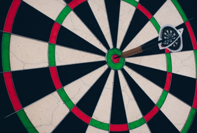 A dartboard with a dart hitting the bull’s eye. 
