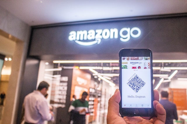 A person holds a black smartphone at an Amazon store.
