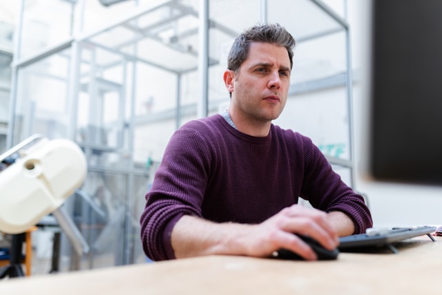 A man looks confused while he searches for someone on TikTok on his computer. 