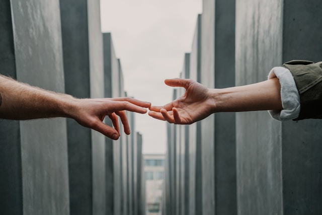 Zwei Arme strecken sich aus und berühren die Finger des jeweils anderen. 