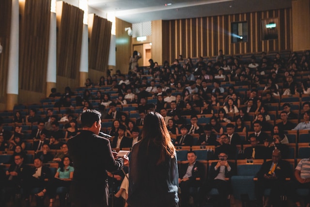 Zwei Personen sprechen vor einem großen Audienzsaal in einem Konferenzsaal. 
