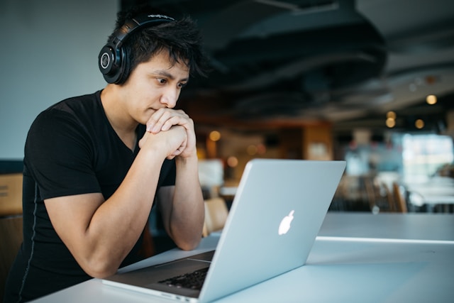 Un homme regarde son ordinateur portable d'un air confus.