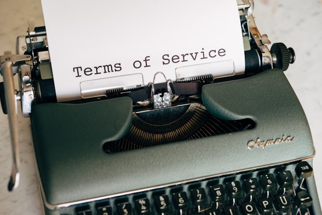 A piece of paper with the words “Terms of Service” printed on it is inserted into a typewriter.