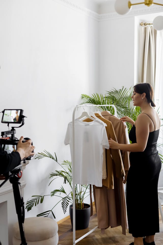 Une femme enregistre une vidéo montrant une étagère de vêtements.