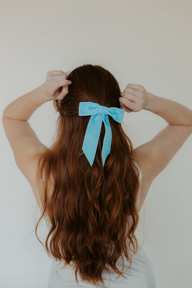 Blue hair bow in woman’s brown hair.
