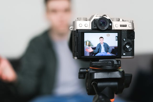 A digital camera screen shows a man speaking.
