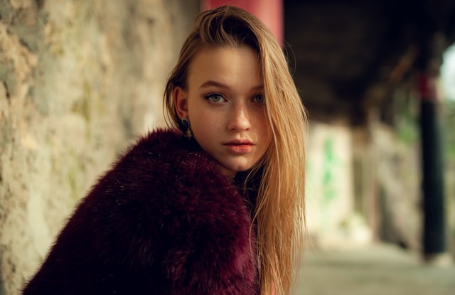 A female influencer models a burgundy fur coat. 
