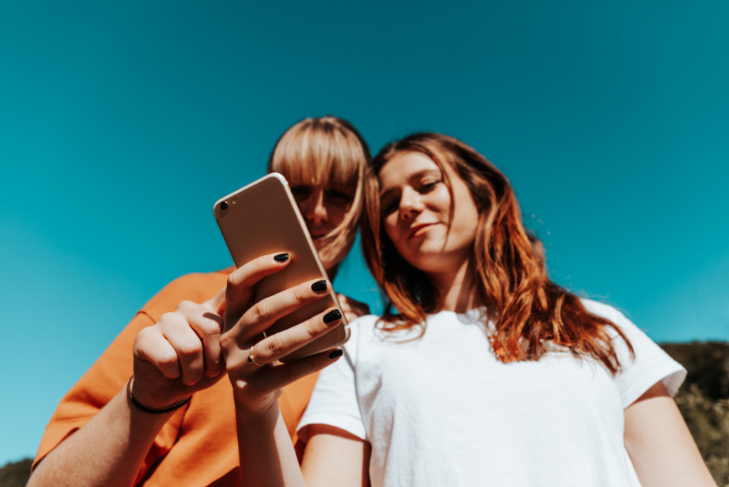Two girls looking intently at a phone, both curious.